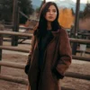 Monica Dutton Suede Leather Coat in front of a wooden fence