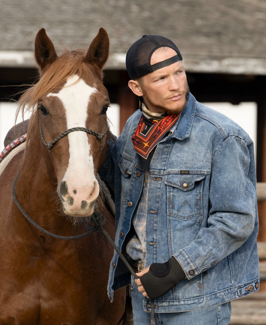 Jimmy Hurdstrom denim jacket standing next to a brown horse with a white stripe on its face.