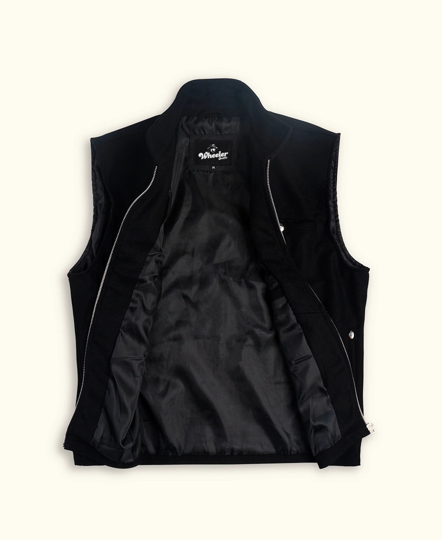 Black vest with open white zippers on a light beige background