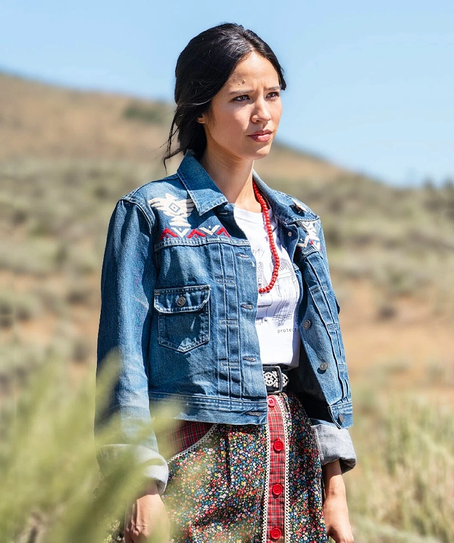 Woman wearing a denim jacket with embroidered designs in an outdoor setting full Image