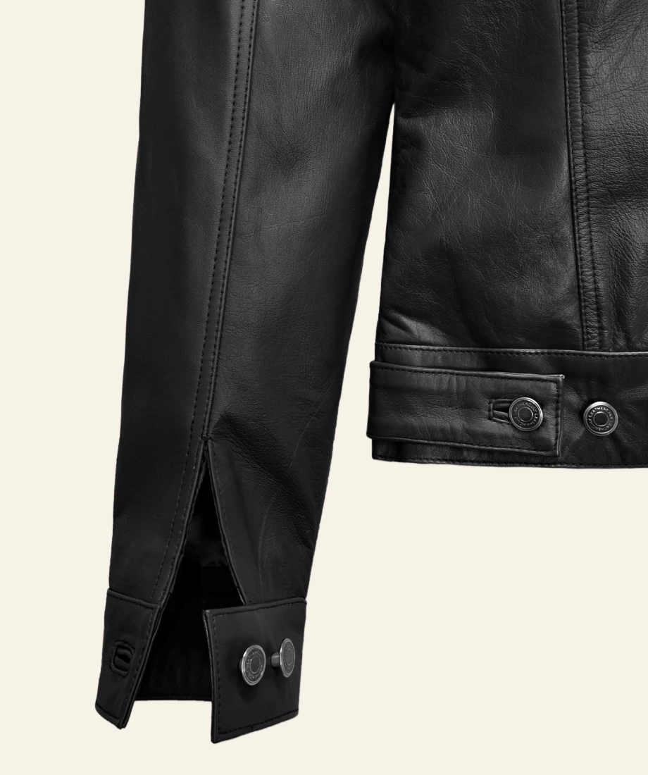 Close-up of a black leather jacket with buttons on a beige background